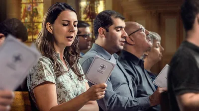 A group at church, reciting a prayer from a prayer book.