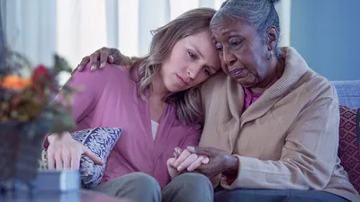 An older sister embracing and comforting a younger sister.