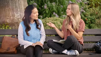 The sister from the preceding image, conducting a Bible study on an outdoor bench with the young woman who was smoking. The sister listens attentively as the woman expresses herself.