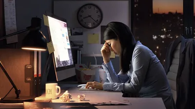 One of the young women looking tired and stressed as she sits in front of a computer late at night.