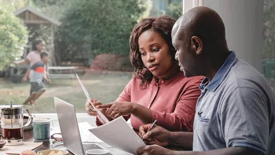 Parents discussing their finances while their children play in the backyard.