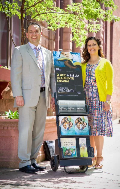 Two of Jehovah’s Witnesses use a mobile display cart in the public ministry