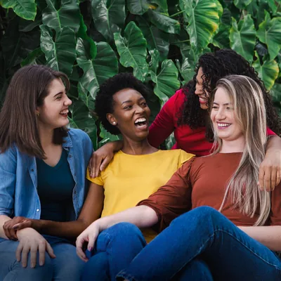 Women of different racial backgrounds laughing and enjoying one another’s company.