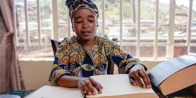 A blind sister using her hands to read a braille publication.