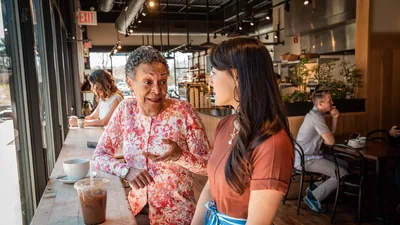 A younger sister listening intently to an older sister at a restaurant.