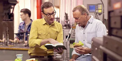 A brother reading a scripture from the Bible to a man at his workplace during their lunch break.