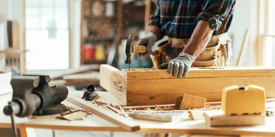 A carpenter hammering a nail into a piece of wood.