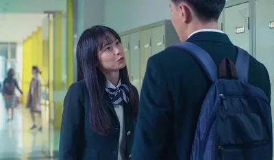 Mee-Kyong talking to Jin in a school hallway.