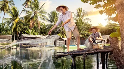 A brother, with his son nearby, casting a fishing net from a pier.