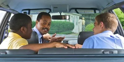 A mature brother talking with two young brothers as they sit in a car.