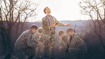 A clergyman praying for a group of soldiers.