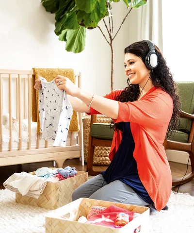 A mother listens to an audio recording of the Bible while she folds her little girl’s clothes