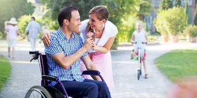 A man in a wheelchair gives his wife a flower