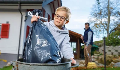 A boy puts trash in a bin