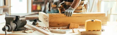 A carpenter hammering a nail into a piece of wood.