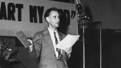 A scene from the video “Our History in Motion​—The Gift of Song, Part 2.” Brother F. W. Franz announces the release of the “Kingdom Service Song Book.”