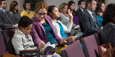 A sister helping her children to comment and follow along during a congregation meeting.
