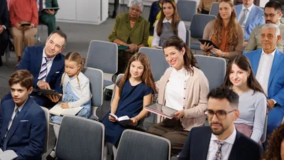 Brothers and sisters of various ages paying close attention to a meeting in the Kingdom Hall.