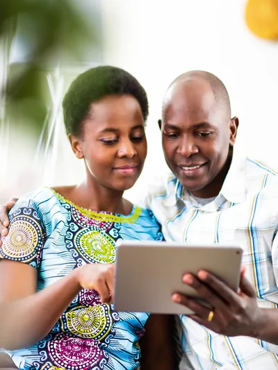A husband and wife reading together on their electronic tablet.