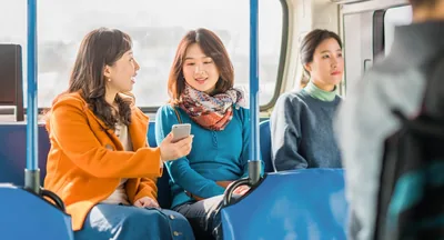 A sister using her phone to witness to a woman on a bus.