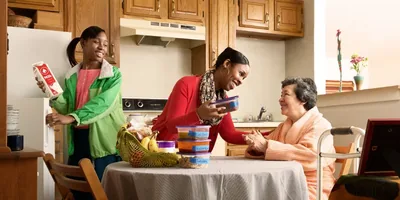 A sister and her daughter bring food to an elderly sister