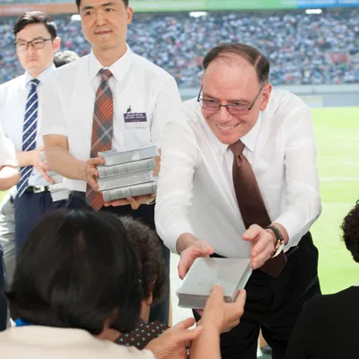 Brother Splane joyfully giving a Bible to a sister.