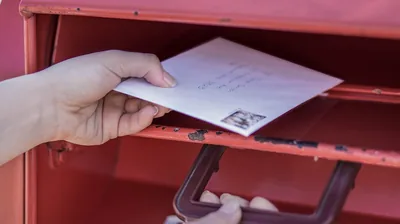 A sister puts a letter in a mailbox