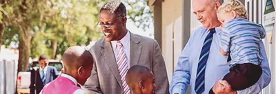 Johny and Gideon greeting children outside a Kingdom Hall of Jehovah’s Witnesses.
