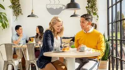 A couple sitting together in a café. They chat happily.