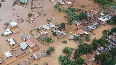 A scene from the video “Devastating Flooding in Brazil.” An aerial view of partially submerged houses and trees in a flooded neighborhood.