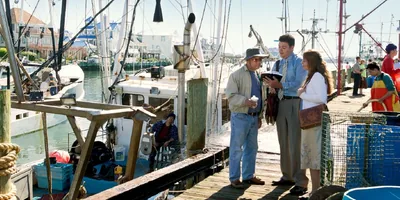 A couple preaching to a man standing on a fishing pier.