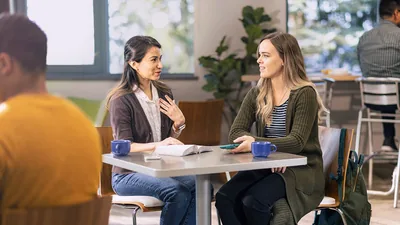 A sister witnessing to a woman at a café.