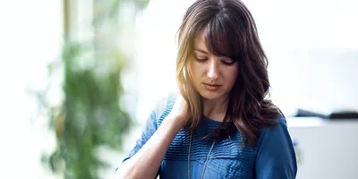 A stressed woman at work bending her head down and looking very sad.