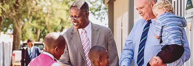 Johny and Gideon greeting children outside a Kingdom Hall of Jehovah’s Witnesses.