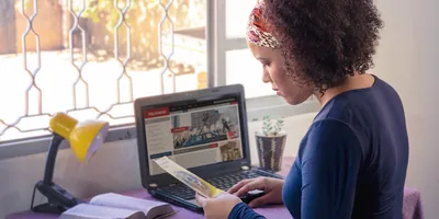 A sister preparing for the ministry. She is holding a tract and browsing the news on her computer.