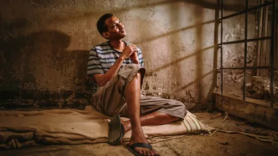 A brother confidently looking upward as he prays from the floor of a prison cell.