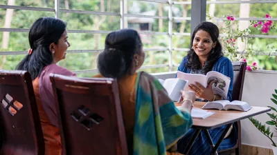 Two of Jehovah’s Witnesses studying the Bible with a woman, using the book “Enjoy Life Forever!”