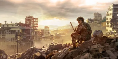 A soldier reflecting as he sits amid the rubble of a city that has been destroyed by war.