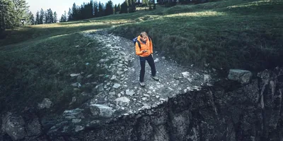 The young man pictured in the previous article using a compass while hiking along a path. He arrives at the edge of a cliff.