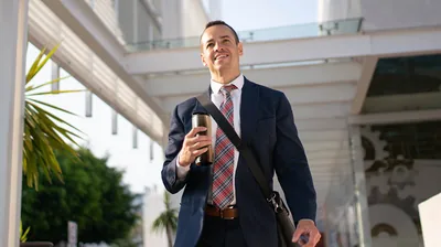 The businessman who earlier lost his job, smiling and walking confidently.