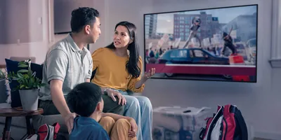 A family watching news of civil unrest on TV. They have emergency go bags nearby.