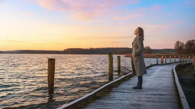 A woman standing on a pier and looking up to the heavens.