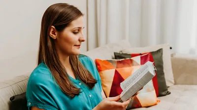 The woman who earlier recited prayers from a book, reading her Bible at home.