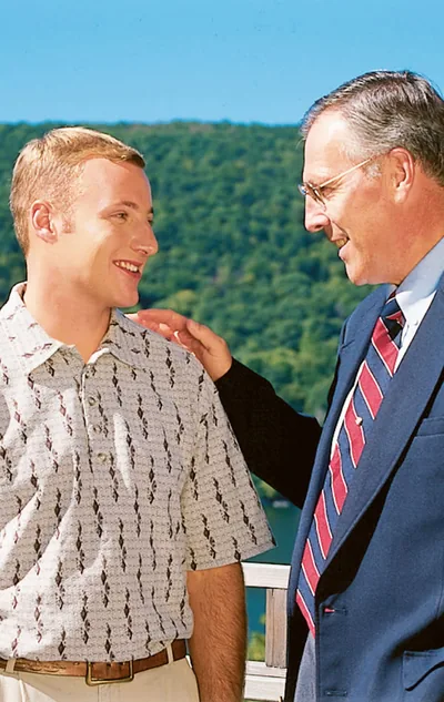 A smiling older brother gently patting a younger brother on the shoulder.
