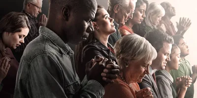 People of various races and ages praying.
