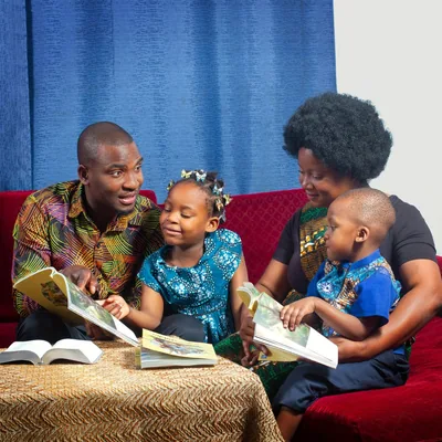 A father conducting family worship with his wife and two young children.
