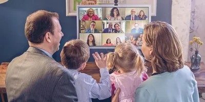 Parents and their two young children associating with their congregation via videoconferencing.