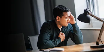 A distressed young man holding his hand to his chest as he prays.