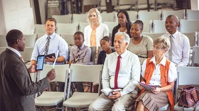 An older brother and his wife listen as a younger brother conducts a meeting