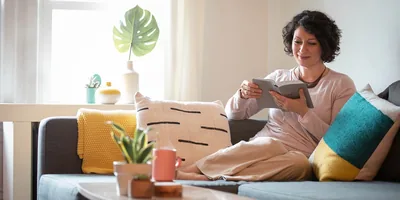 A woman sitting comfortably on a sofa, reading the Bible.